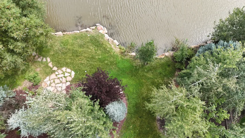Landscaped property perimeter featuring a stone pathway and diverse plantings