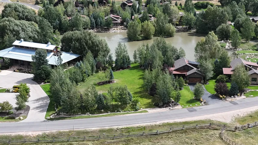 Expansive property featuring a paved driveway, lush green landscaping, mature trees, and a tranquil pond
