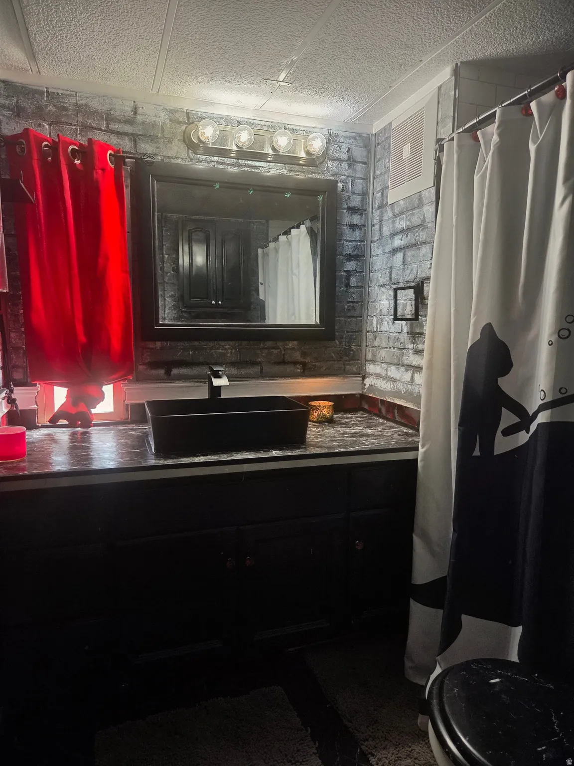 Black vanity with a rectangular vessel sink, coordinating countertop, and framed mirror