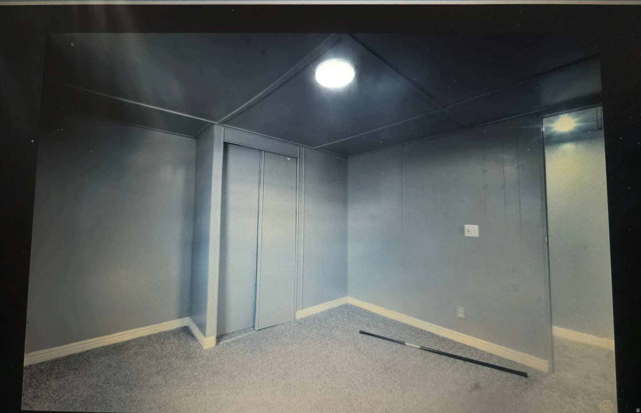 Recessed lighting, light gray paneled walls, white trim, and light gray carpeting