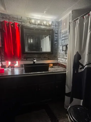 Black vanity with a rectangular vessel sink, coordinating countertop, and framed mirror
