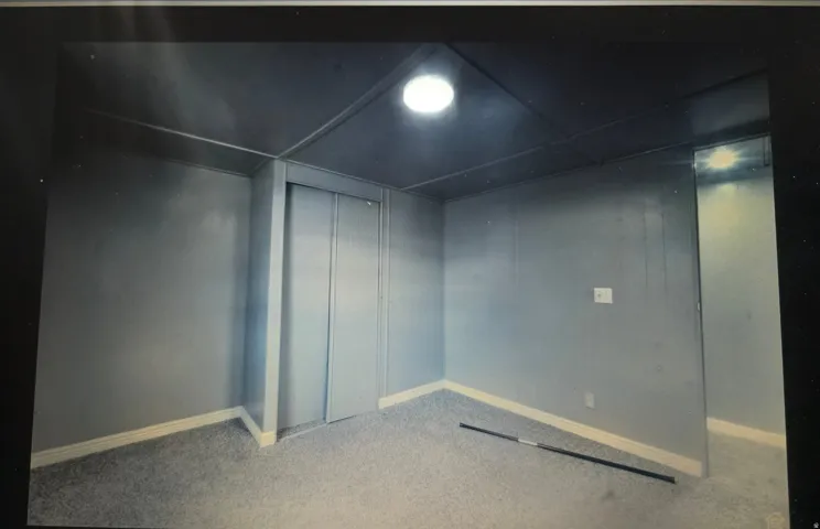 Recessed lighting, light gray paneled walls, white trim, and light gray carpeting