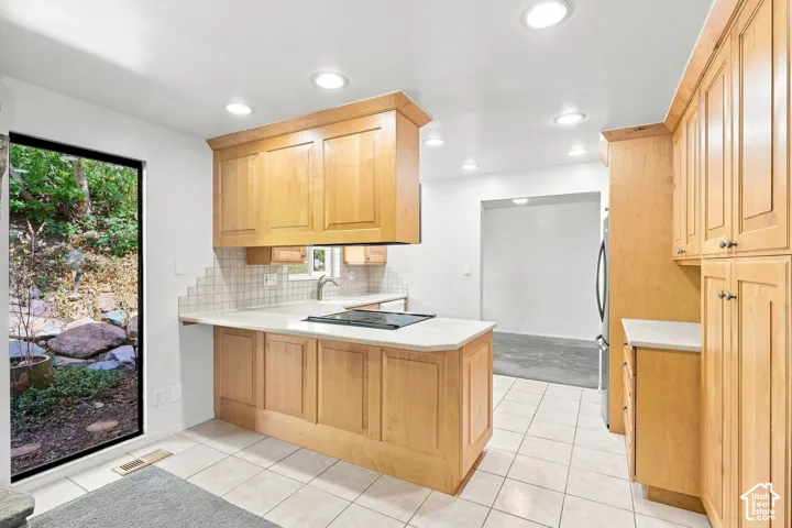 Kitchen featuring wood cabinetry, light-toned countertops, and tile flooring