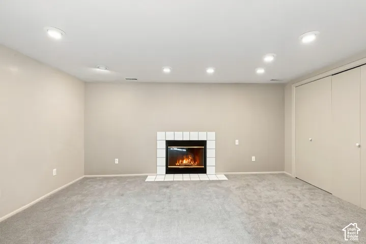 Recessed lighting throughout, wall-mounted fireplace with white tile surround, and built-in closet storage