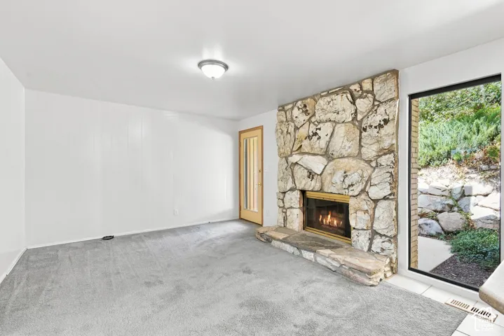 Stone-clad fireplace with a hearth, full-height window, white paneling, and ceiling-mounted light fixture