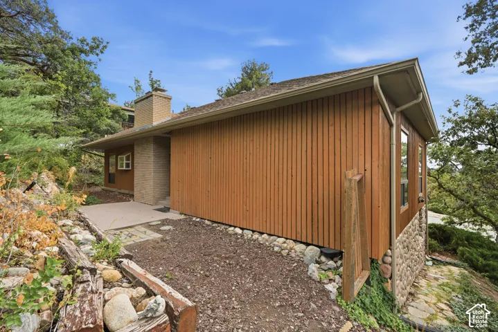 Wood-paneled exterior with a brick chimney and stone foundation accents