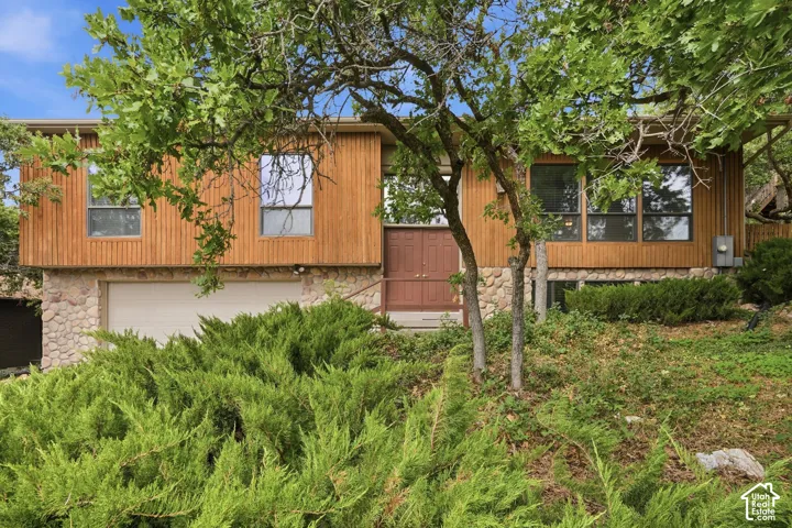 Wood panel siding exterior with stone accents, integrated garage, and a double entry door