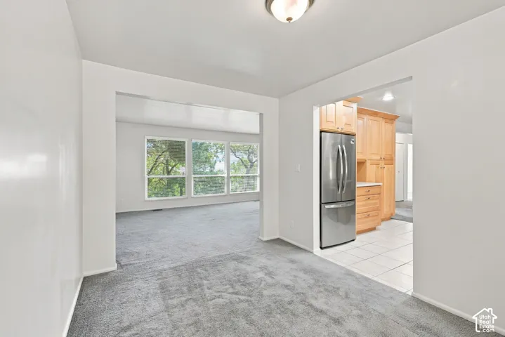 Open-concept layout with carpeted living space and tile flooring