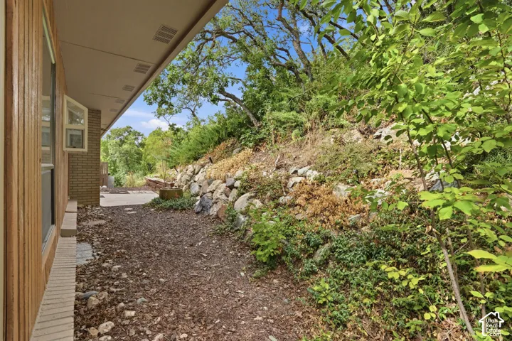 Wood-paneled exterior with a brick foundation, covered walkway, and rock retaining wall