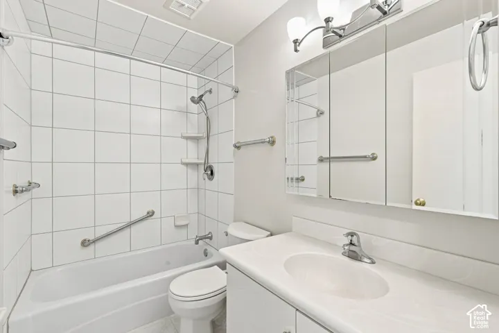 White tile surround shower-tub combination, vanity with integrated sink, tri-fold mirrored medicine cabinet, and wall-mounted vanity lighting