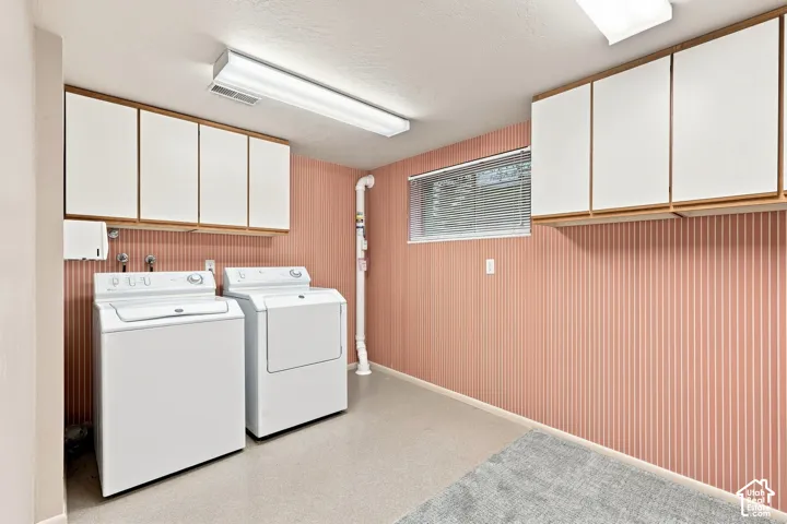 Laundry area featuring wall-mounted cabinetry, a window with blinds, and durable flooring