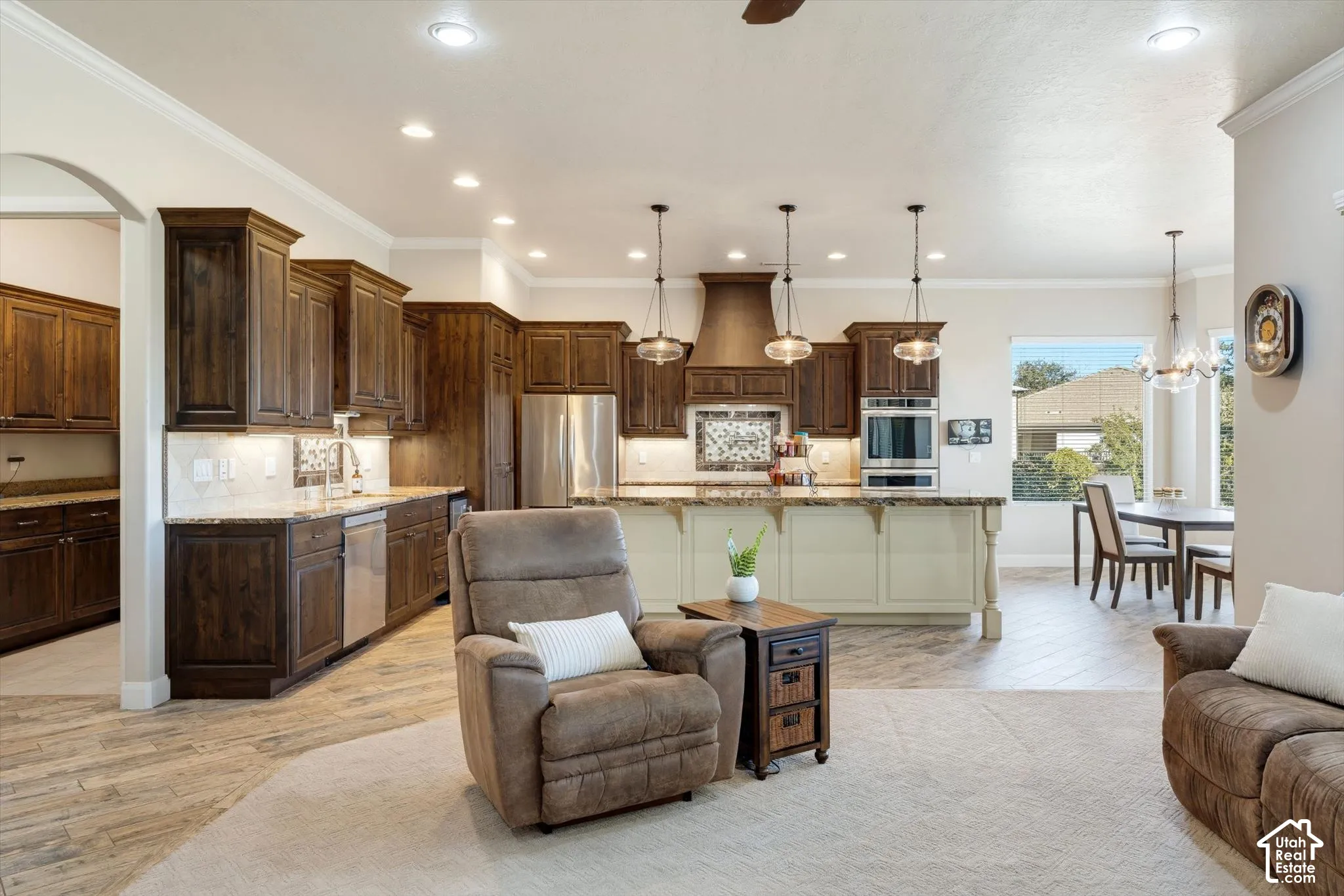 Open-concept living space featuring wood-finish flooring, recessed lighting, and crown molding