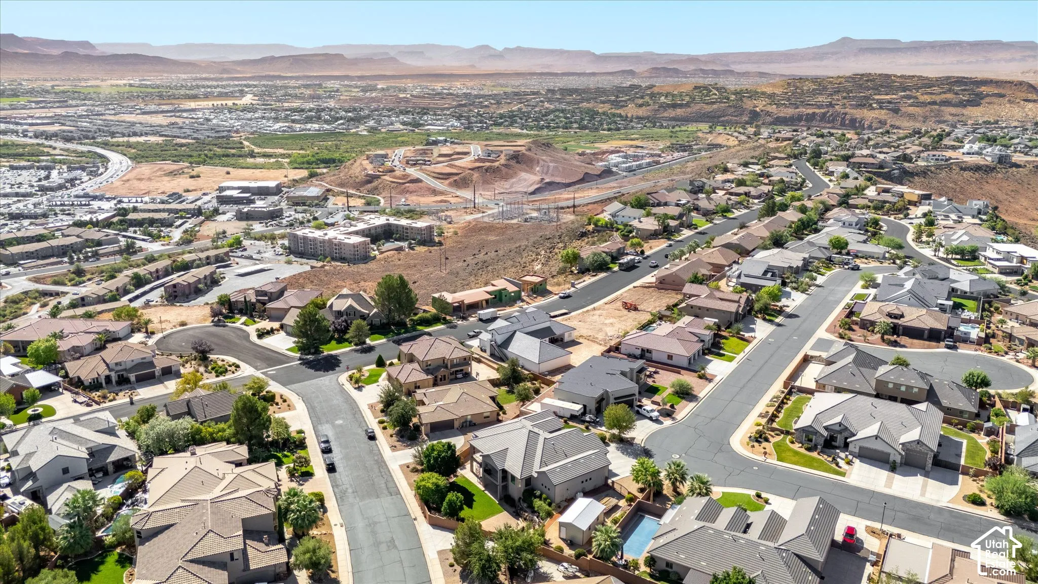 Expansive residential development with a variety of architectural styles, surrounded by natural desert landscapes and distant mountains
