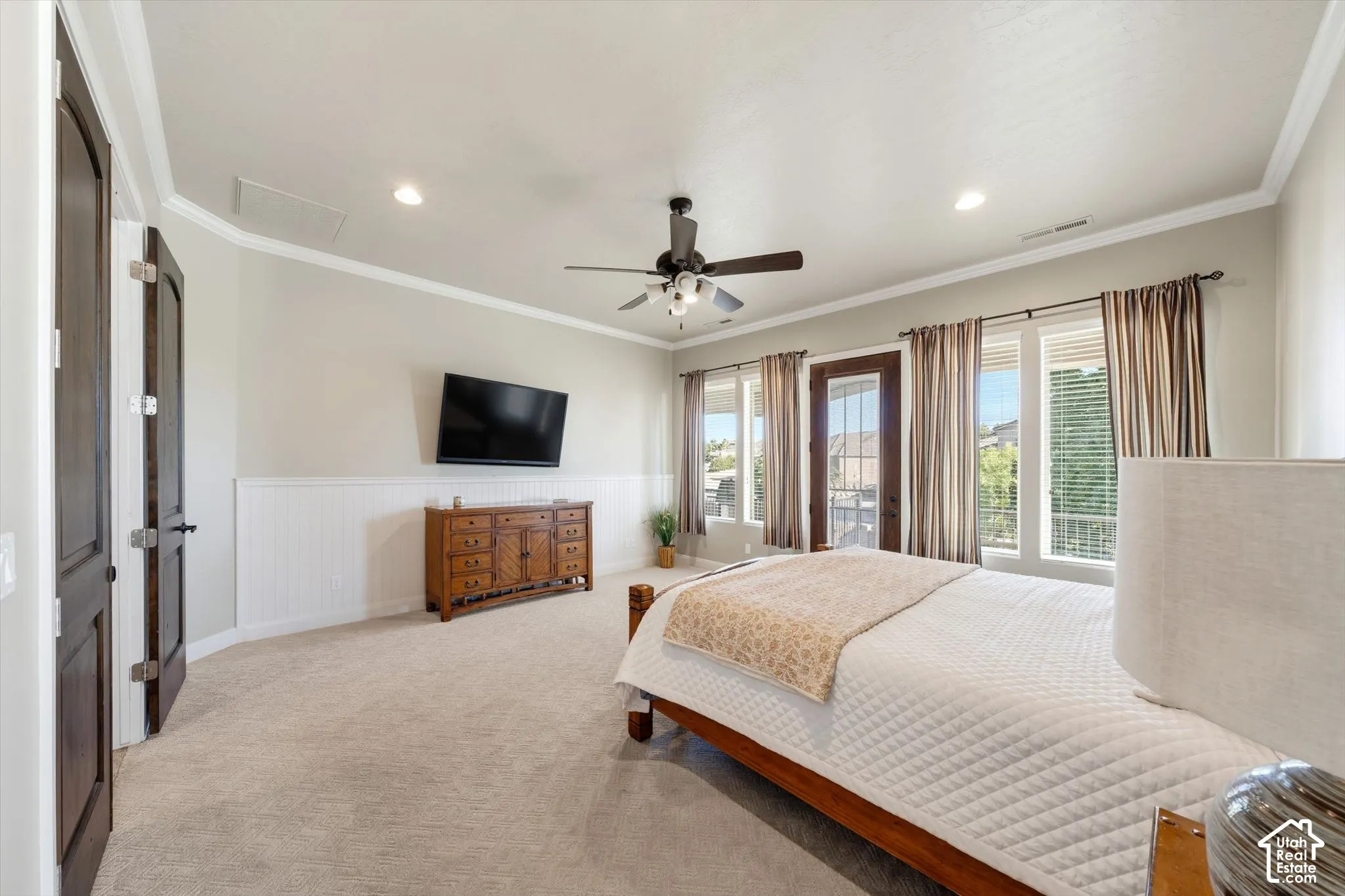 Light-toned carpeting, white wainscoting, and crown molding