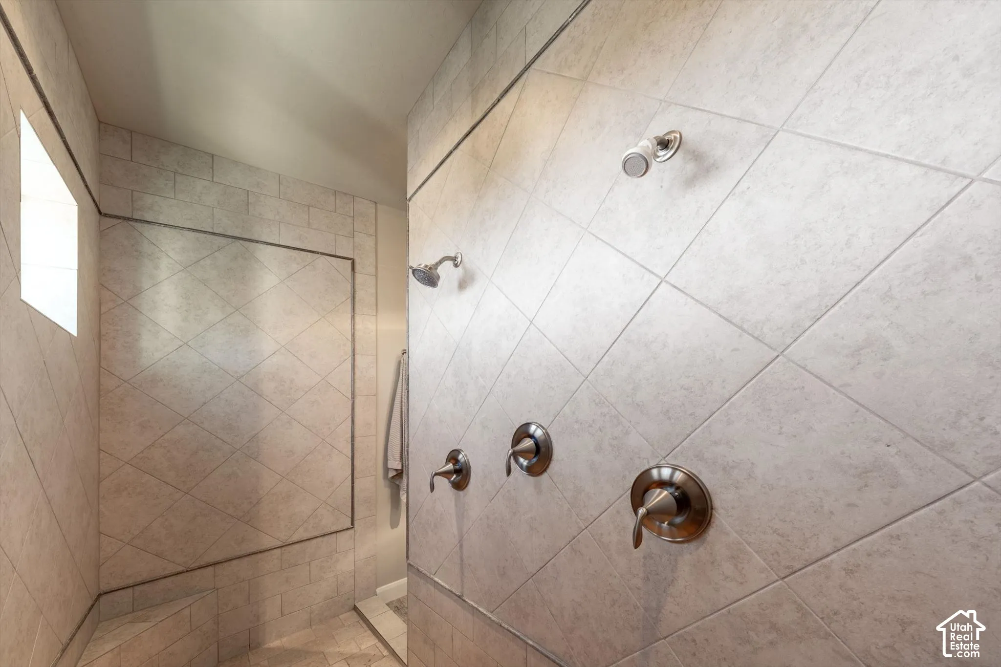 Tiled shower enclosure featuring multiple shower heads, an integrated bench, and a privacy window