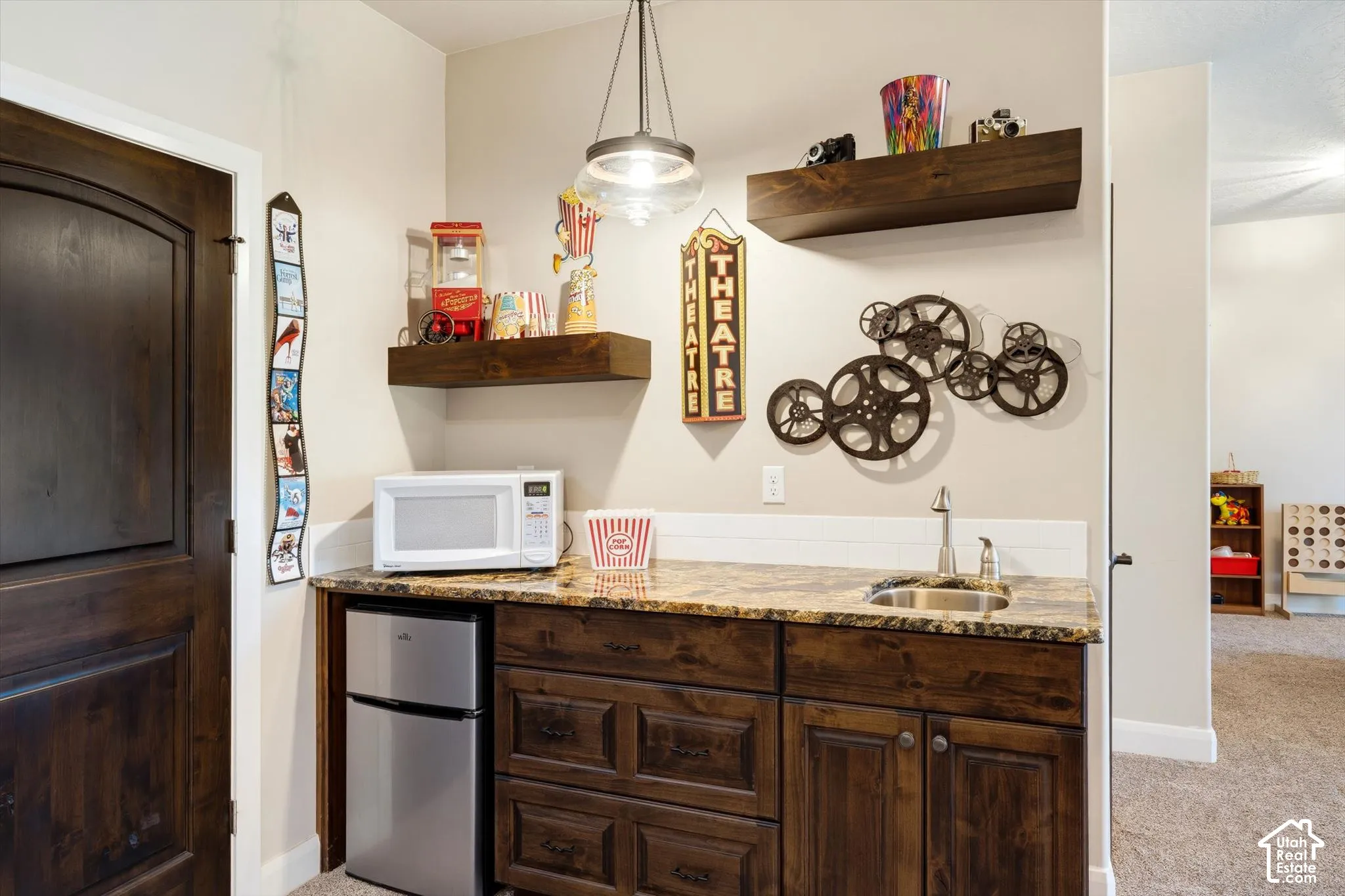 Built-in wet bar featuring a stainless steel sink, granite countertop, and wood-finish cabinetry