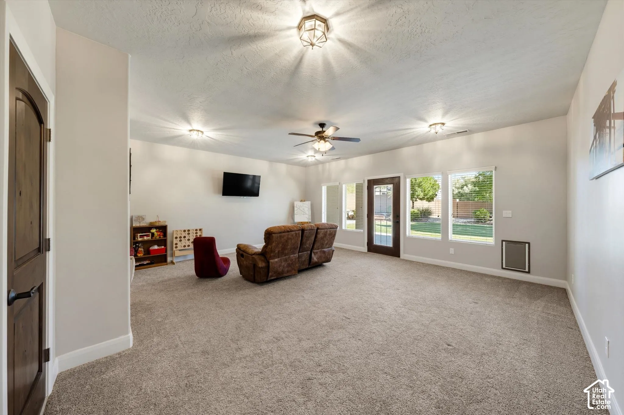 Expansive room featuring light-colored walls, recessed lighting, and a ceiling fan
