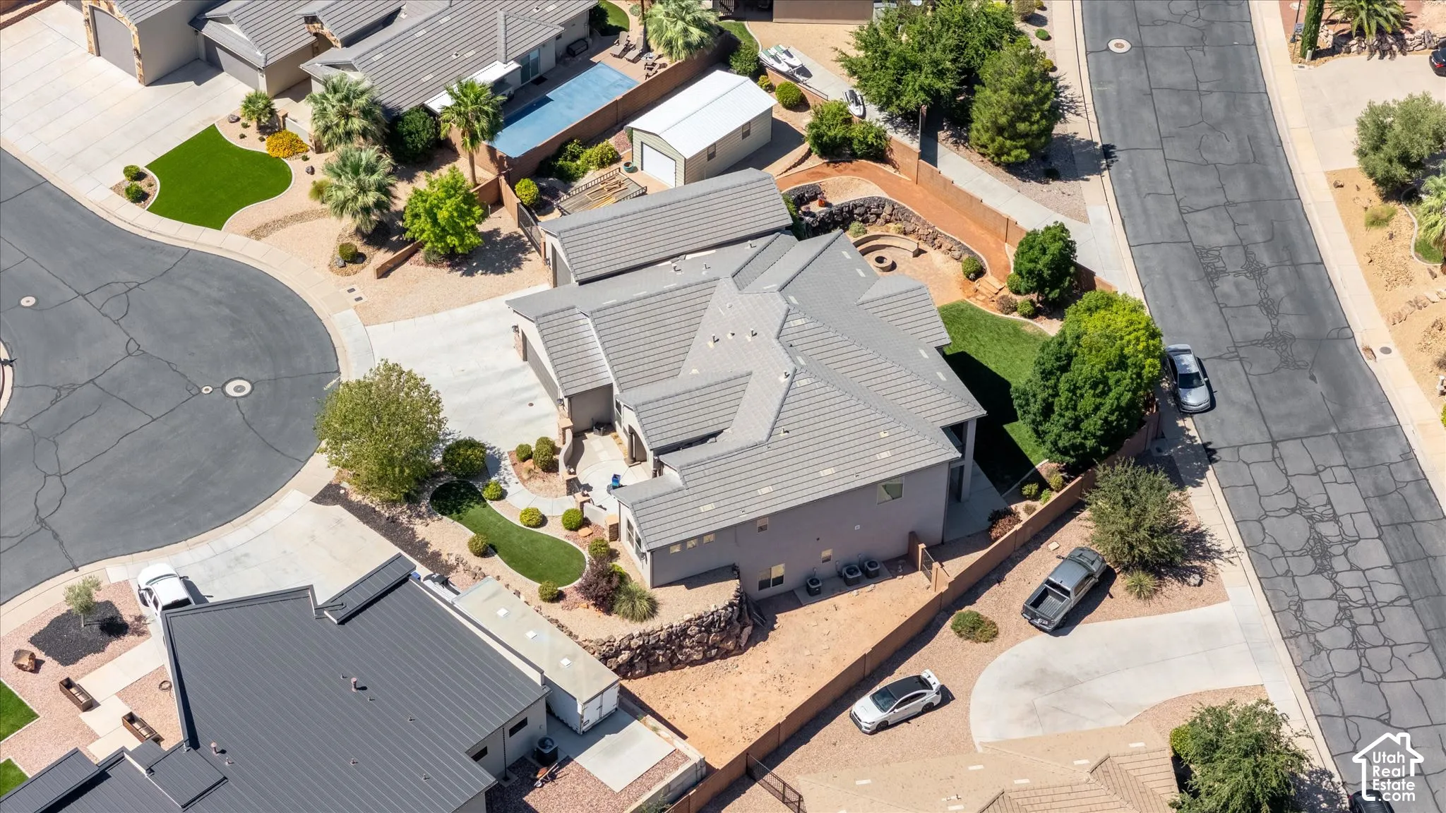 Light gray tiled roof, landscaped front yard, paved driveway, landscaped backyard with fire pit, and partial hardscaping
