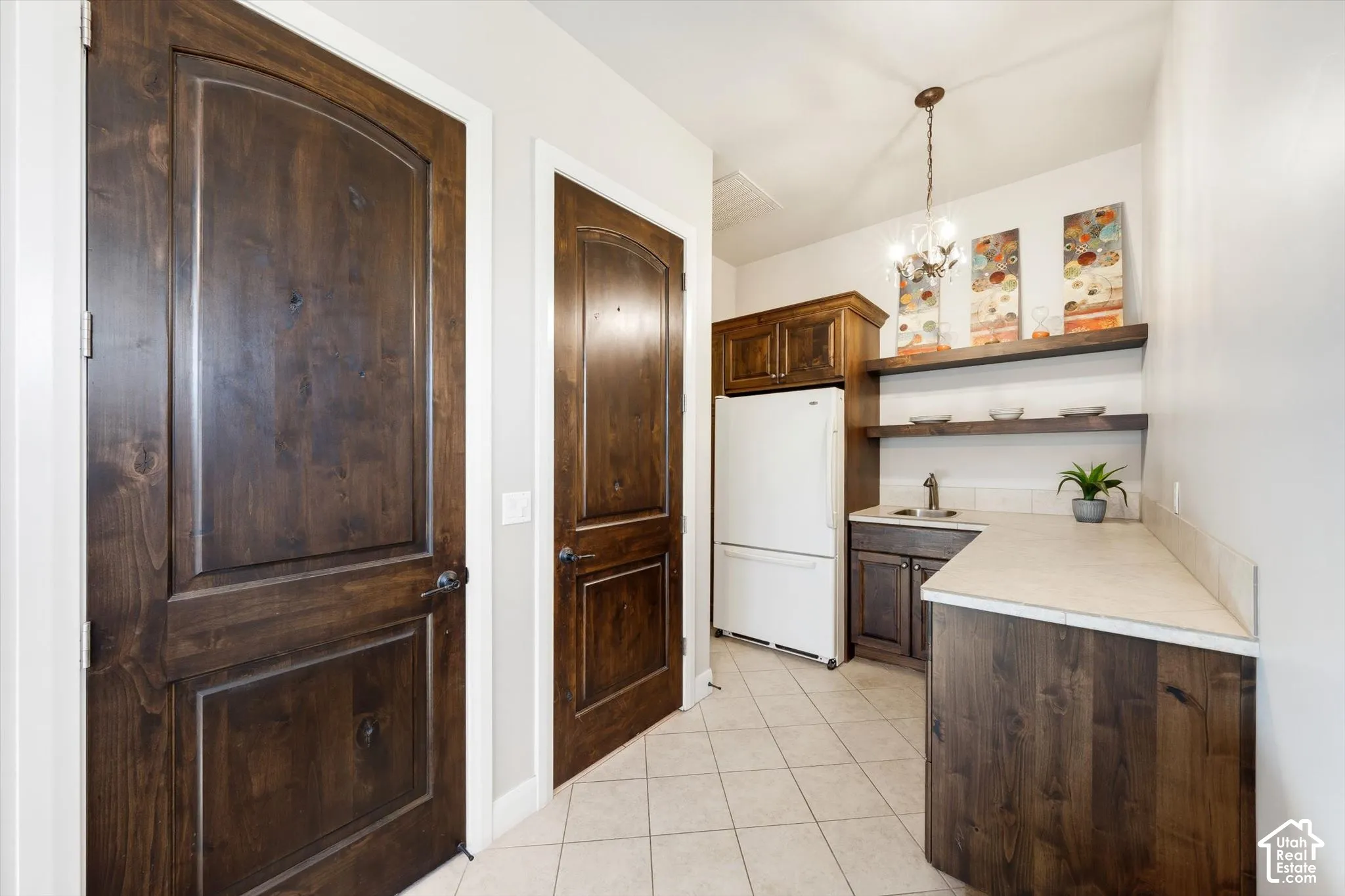 Kitchenette with wood-finish cabinetry, light-toned countertop, and tile flooring