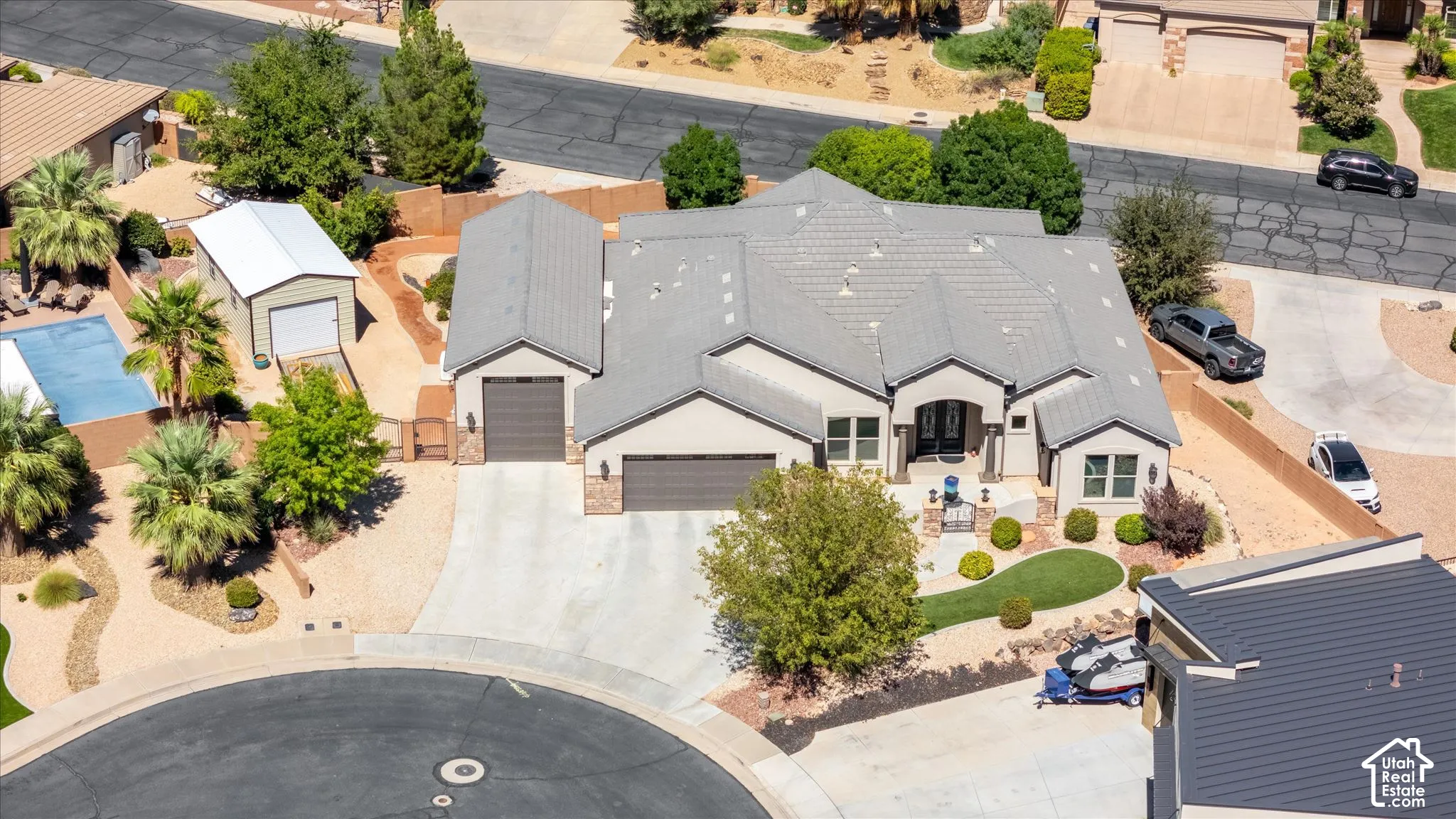 Stucco exterior with stone accents, covered entry, attached multi-car garage, and a tiled roof