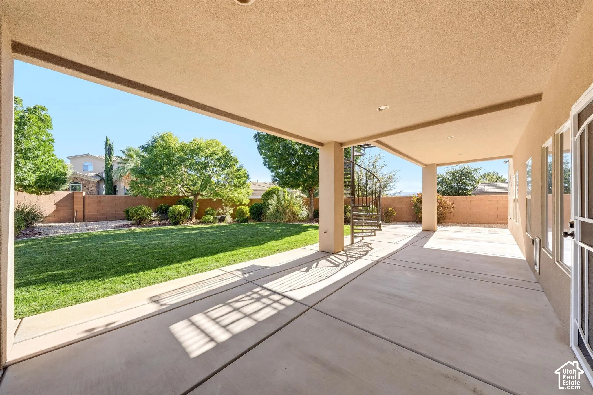 Expansive covered patio with concrete flooring, recessed lighting, and a spiral staircase