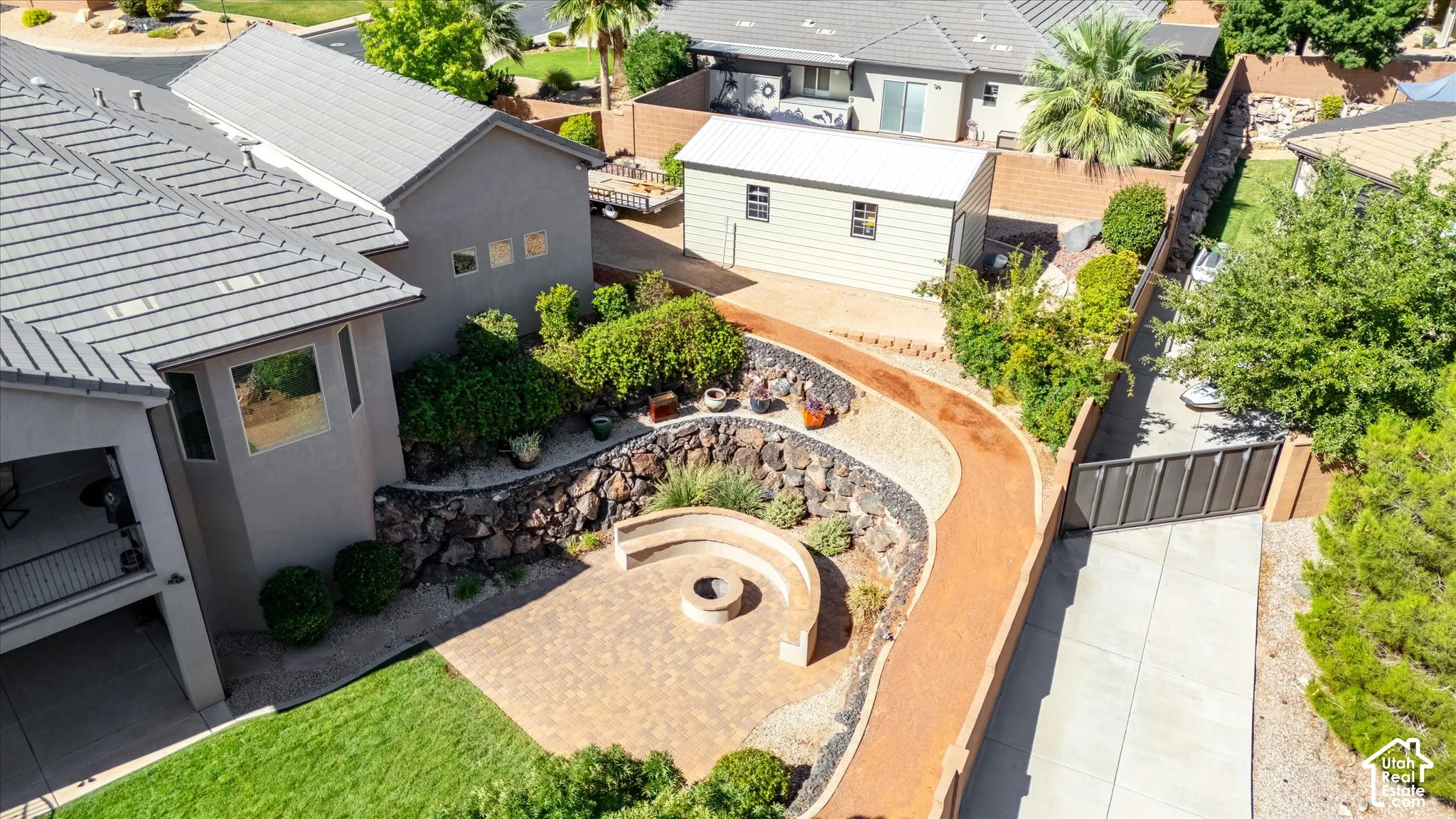 Expansive backyard featuring a paver patio with built-in seating and a fire pit, a gravel pathway, and mature landscaping