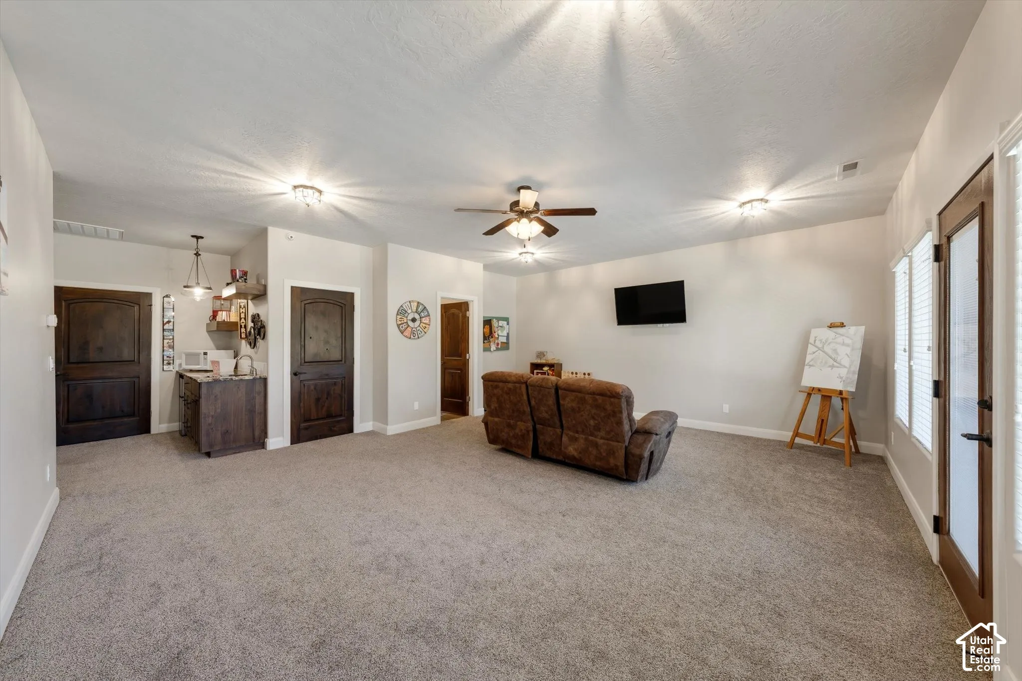 Spacious room featuring neutral carpeting, a built-in wet bar with dark wood-finish cabinetry, and multiple recessed light fixtures
