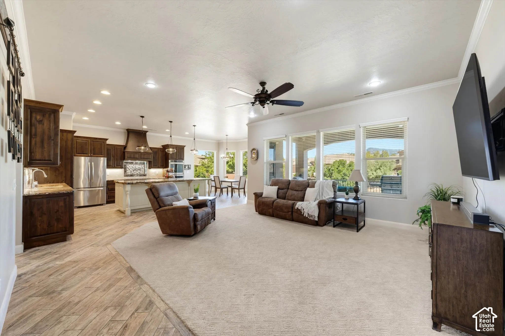 Spacious open-concept layout featuring wood-finish flooring, a kitchen island with pendant lighting, stainless steel appliances, and large windows