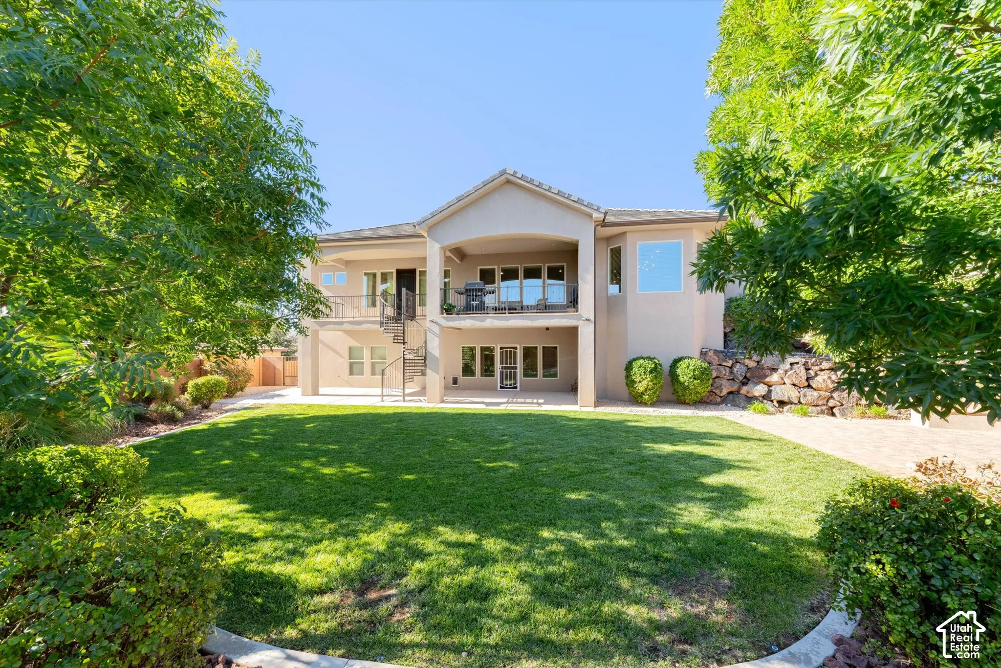 Expansive backyard with a manicured lawn, established perimeter landscaping, and mature trees