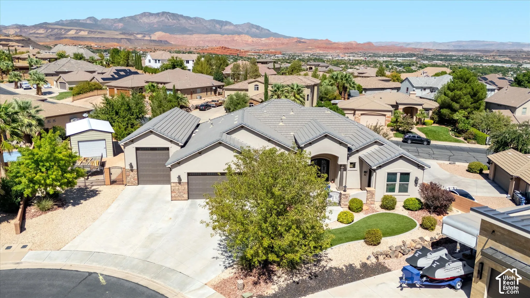 Stucco exterior with stone accents, hip and gable rooflines, attached two-car garage, and a manicured front yard with mature landscaping