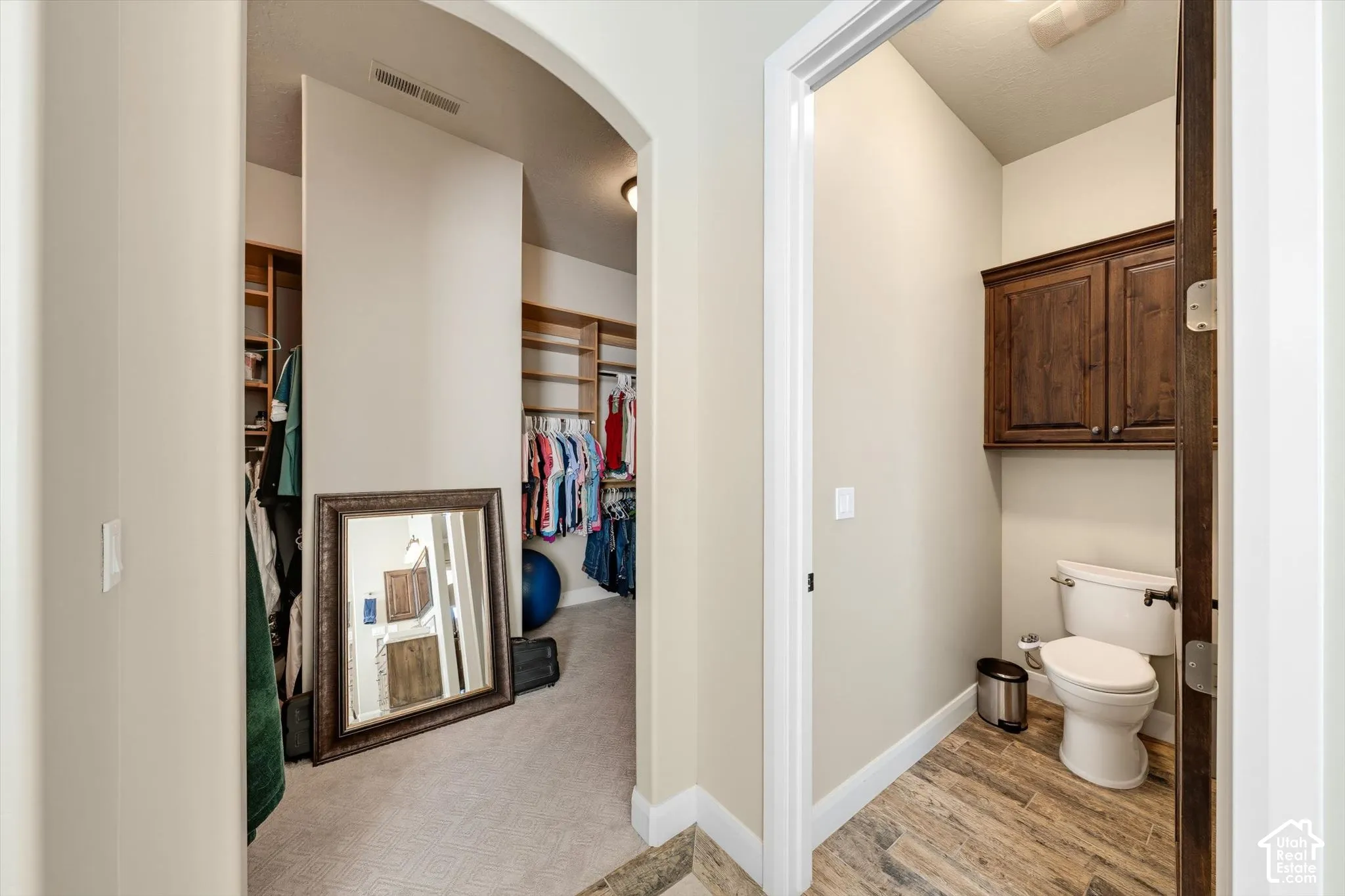 Hallway featuring an arched entryway, recessed lighting, and carpeted flooring leading to a walk-in closet with built-in wooden shelving