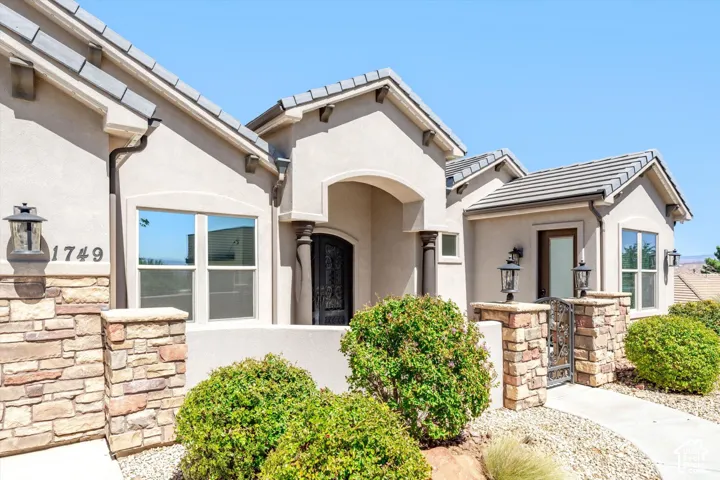 Stucco exterior with stone accents, tile roof, arched entry, and decorative wrought iron details