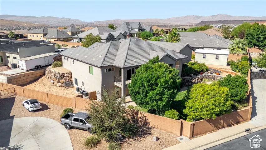 Multi-level residence with a tile roof, stucco exterior, and a terraced backyard featuring mature landscaping