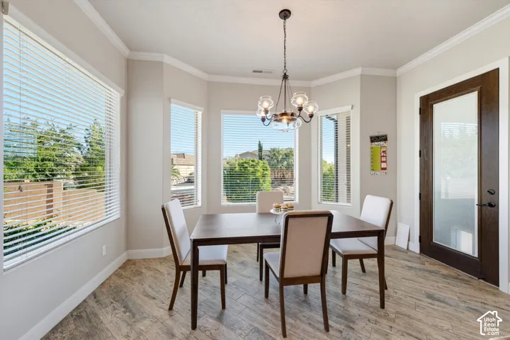 Bay window with multiple large windows, wood-finish flooring, a contemporary chandelier, and a dark wood-paneled door with frosted glass