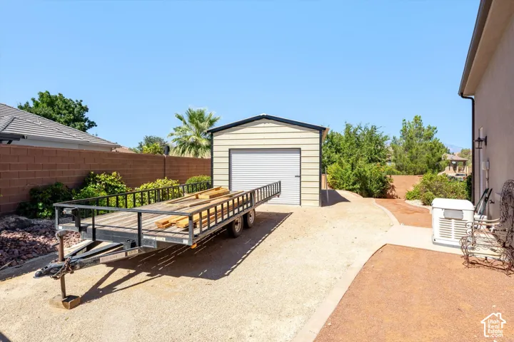 Detached utility shed with roll-up door, gravel surfacing, concrete pathway, and block fencing