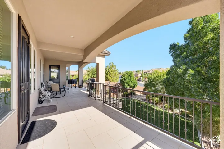 Covered balcony featuring tile flooring, archways, and a wrought iron railing