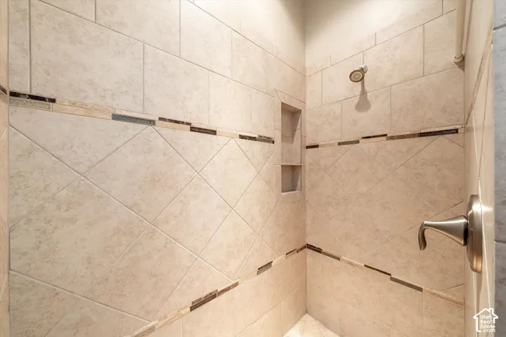 Tiled shower with decorative accent bands, brushed nickel fixtures, and recessed shelving