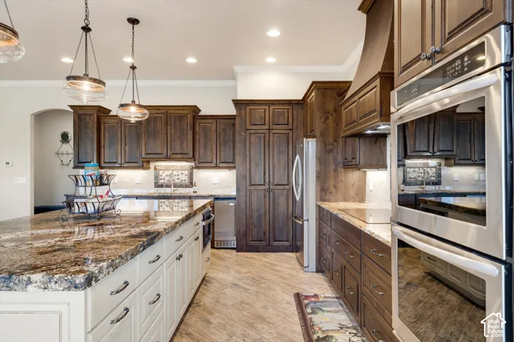 Kitchen featuring an oversized island with a stone countertop, stained wood cabinetry, stainless steel appliances, and recessed lighting