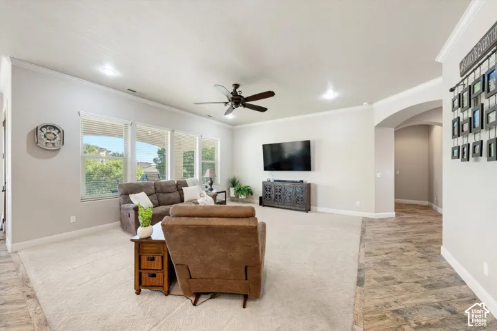Spacious open-concept living area with recessed ceiling lighting, ceiling fan, and large windows providing natural light