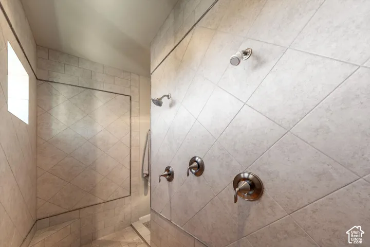 Tiled shower enclosure featuring multiple shower heads, an integrated bench, and a privacy window