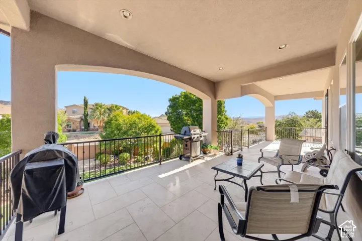 Expansive covered patio with recessed lighting, stucco archways, tile flooring, and black metal railings