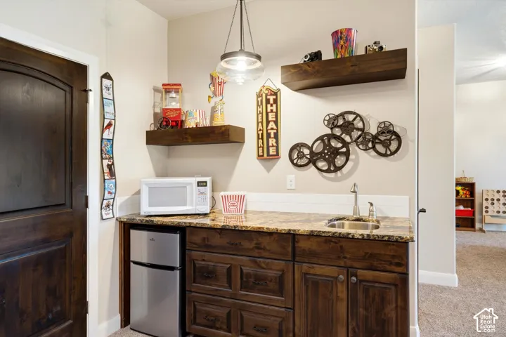 Built-in wet bar featuring a stainless steel sink, granite countertop, and wood-finish cabinetry