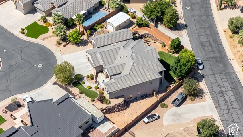 Light gray tiled roof, landscaped front yard, paved driveway, landscaped backyard with fire pit, and partial hardscaping