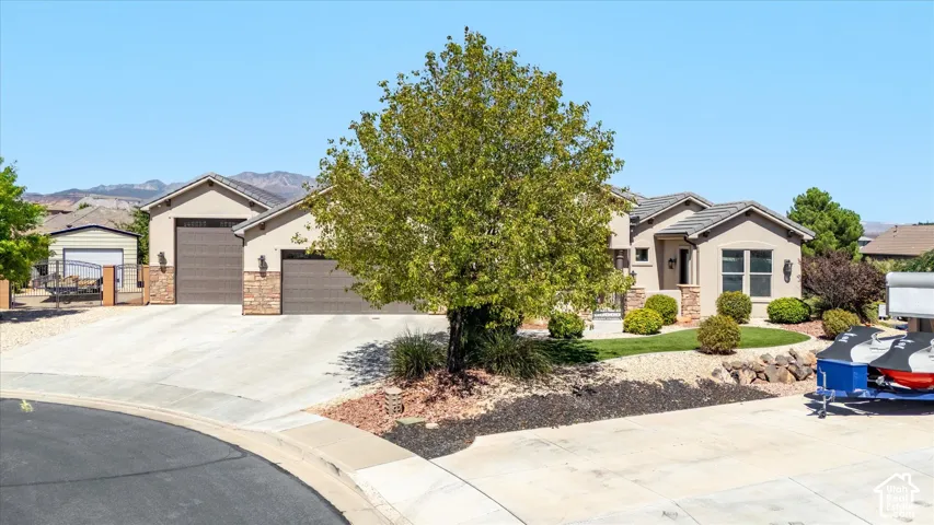 Stucco exterior with stone accents, tile roofing, and a concrete driveway