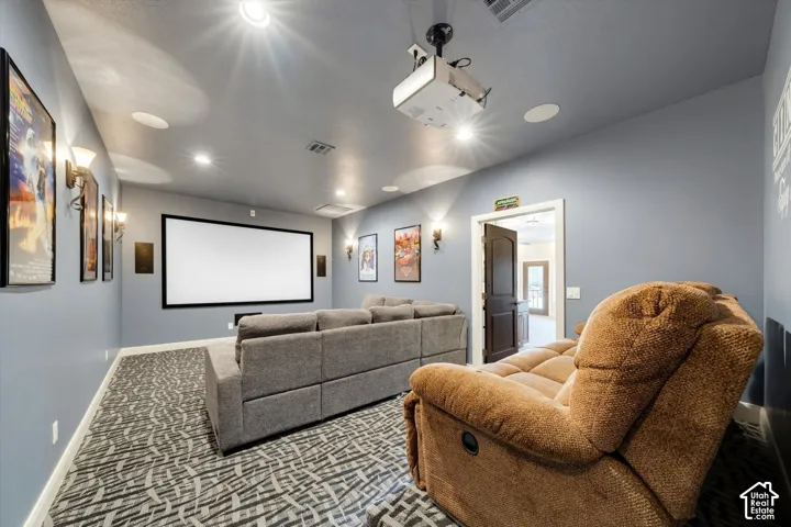 Dedicated media room featuring a large projection screen, mounted projector, recessed lighting, and integrated wall sconces