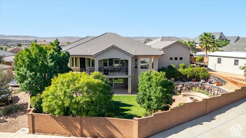 Tiered landscaping with a built-in fire pit, covered patio, upper-level balcony, and a manicured lawn