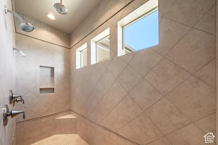 Tiled shower with a built-in bench, recessed shelf, multiple shower heads, and three clerestory windows