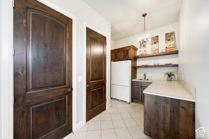 Kitchenette with wood-finish cabinetry, light-toned countertop, and tile flooring