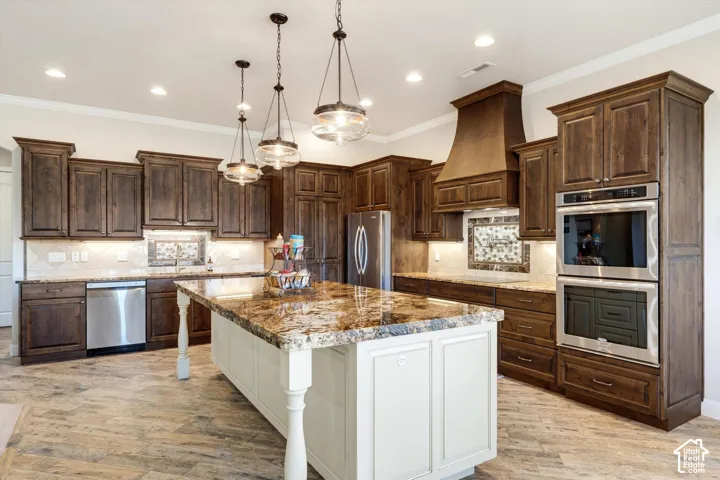 Spacious kitchen featuring an expansive center island with a stone countertop, dark wood-finish cabinetry, stainless steel appliances, and tile flooring
