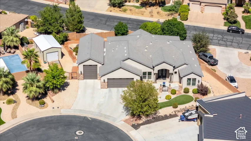 Stucco exterior with stone accents, covered entry, attached multi-car garage, and a tiled roof